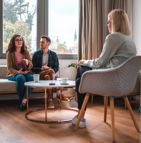 Habitación con una psicóloga y dos personas en una terapia de parejas.