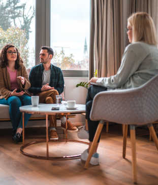 Habitación con una psicóloga y dos personas en una terapia de parejas.